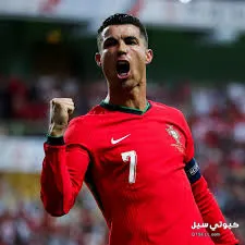 لاعب كرة قدم يرتدي زي المنتخب البرتغالي الأحمر يحتفل على أرض الملعب